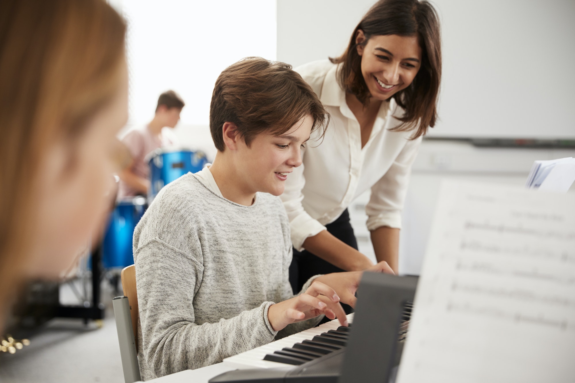 male-pupil-with-teacher-playing-piano-in