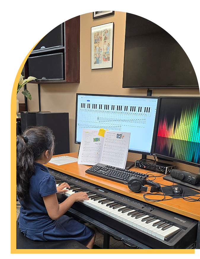 A young girl with long dark hair plays an electronic keyboard in a music classroom during music lessons Westchase, with sheet music in front of her and two large monitors displaying musical notes and a colorful soundwave.